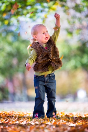 happy little girl throwing fall leavesの写真素材