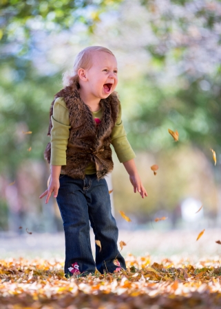 happy little girl throwing fall leavesの写真素材