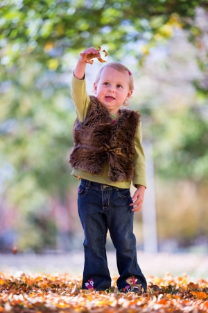 happy little girl throwing fall leavesの写真素材