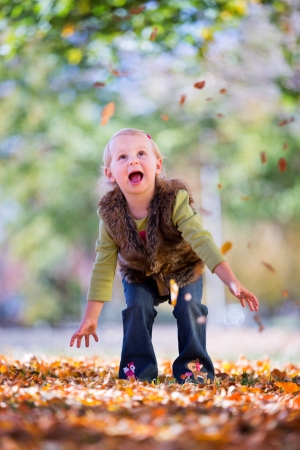 happy little girl throwing fall leavesの写真素材