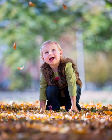happy little girl throwing fall leavesの写真素材