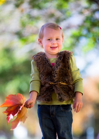 cute little girl with fall leavesの写真素材