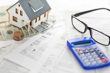 Miniature house with money on tax papersの写真素材