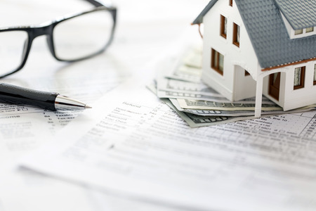 Miniature house with money on tax papersの写真素材