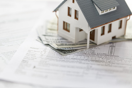 Miniature house with money on tax papersの写真素材