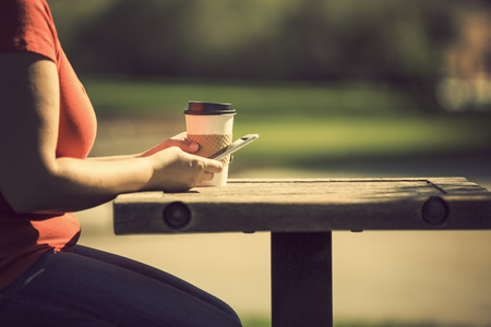 Morning at the park with take away coffee and smart phoneの写真素材