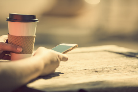 Morning at the park with take away coffee and smart phoneの写真素材