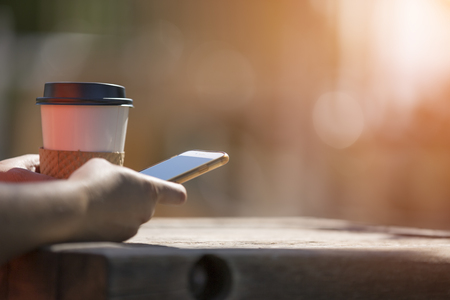 Morning at the park with take away coffee and smart phoneの写真素材