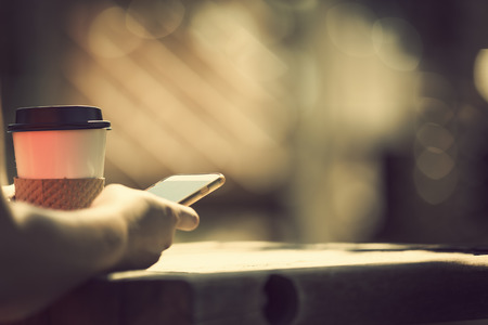 Morning at the park with take away coffee and smart phoneの写真素材