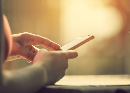 Smart phone in hands in bright sunlightの写真素材