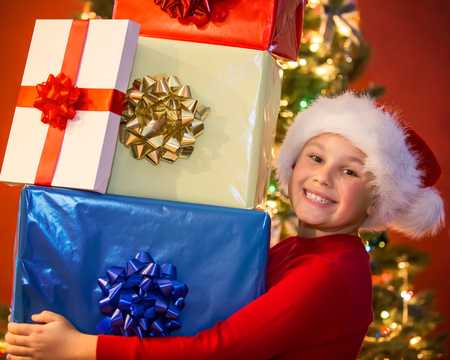 Happy boy holding many Christmas giftsの写真素材
