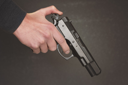 Man's hand holding gun over dark backgroundの写真素材