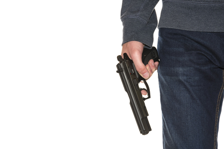 Armed person holding handgun wearing dark blue jeans and hoodie isolated on white background, copy space, close-up on gunの写真素材