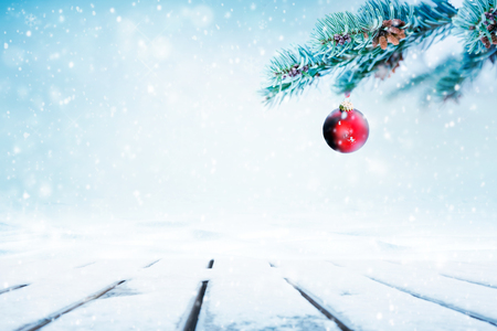 Christmas  with red ornament and falling snow on pine tree branchesの写真素材