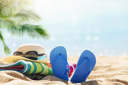 Beach accessories straw hat, flip flops, towel on sunny tropical beach, summer holidaysの写真素材