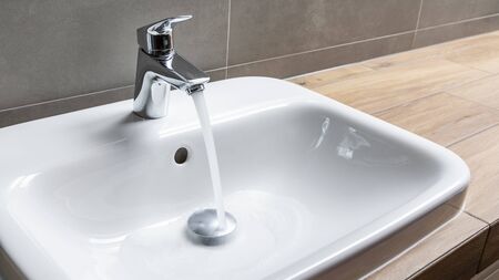 faucet with running water in bathroomの写真素材