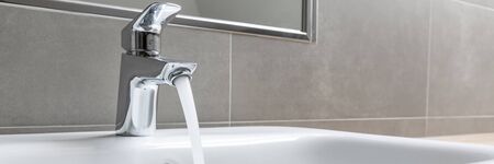 Bathroom faucet with running water into ceramic sinkの写真素材
