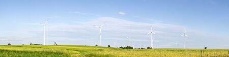 wind turbines in green field, countryside area with blue sky