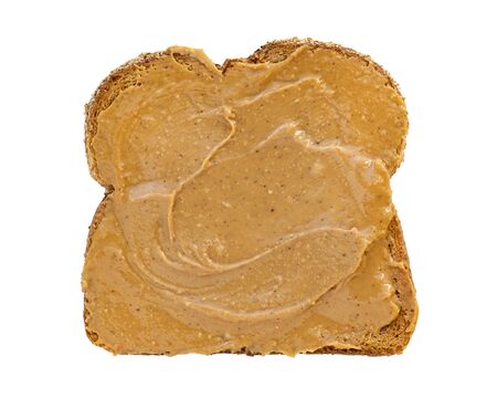Creamy peanut butter spread on healthy whole wheat toast bread, isolated on white background, photographed from aboveの写真素材