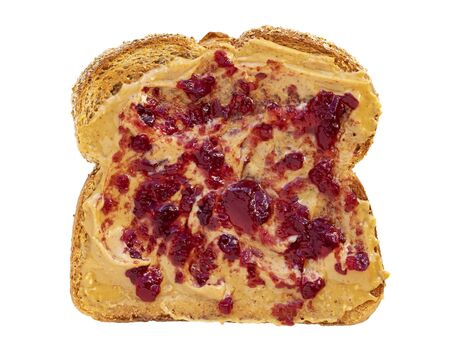 Creamy peanut butter spread with fruit jam on healthy whole wheat toast bread, isolated on white background, photographed from aboveの写真素材