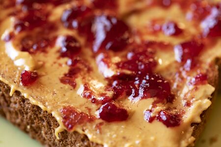 Creamy peanut butter spread with fruit jam on healthy whole wheat toast breadの写真素材