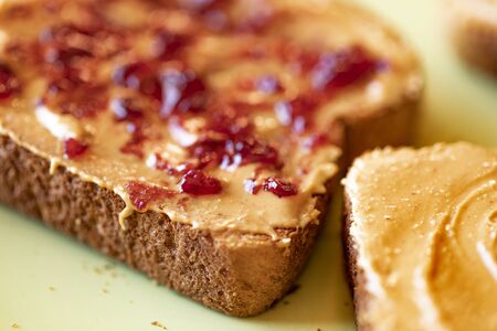 Creamy peanut butter spread with jelly on healthy whole wheat toast bread, close-up