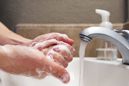 Washing hands with soap and water in bathroom sink, protection against covid-19 coronavirus flu virusesの写真素材