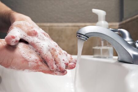 Washing hands with soap and water in bathroom sink, protection against viruses and bacteria, hygiene to stay healthyの写真素材