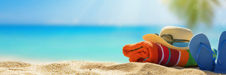 Beach background with flip flops, hat and towel on sandの写真素材