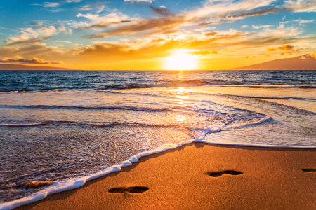 Beautiful sunrise on the beach with footprints in the sand, sea and skyの写真素材