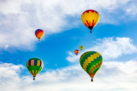 Colorful hot air balloons flying in the blue sky with white cloudsの写真素材