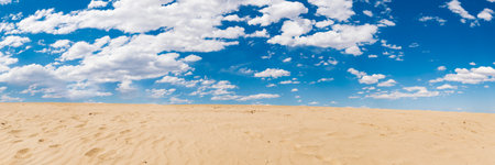 Panorama of sand dunes under blue sky with white clouds.の写真素材