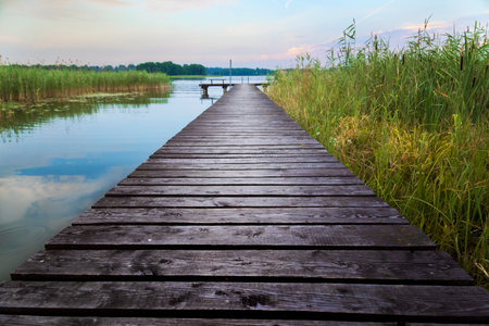 Wooden pier on a lake at sunset. Beautiful summer landscape.の写真素材