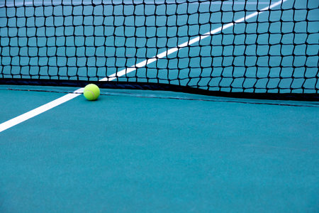 Tennis ball on the court with net in the background, close-upの写真素材