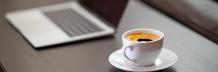 Coffee cup and laptop on table in coffee shopの写真素材