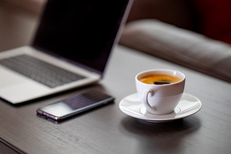 Cup of coffee with laptop and mobile phone on wooden table.の写真素材