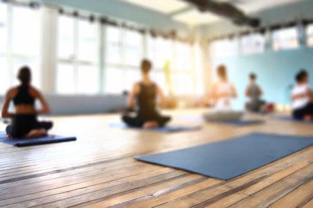 Blurred image of people practicing yoga in gym. Yoga class conceptの素材