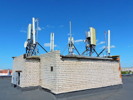 Cell phone antenna on the roof, transmitter. Telecom radio mobile antenna against blue sky 1