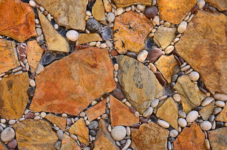 Floor, wall of brown and beige stones laid in a geometric pattern, floor with cracks