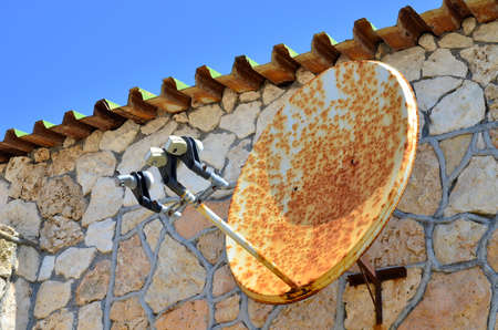 Rusty satellite TV radio internet wifi antenna on the wall of ancient houseの写真素材