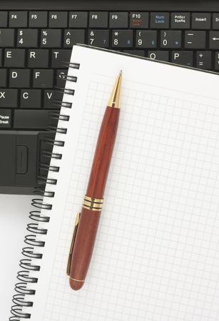 Pen and spiral notepad on black laptop keyboardの写真素材