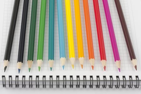 Multicolored pencils on page of opened spiral notebookの写真素材