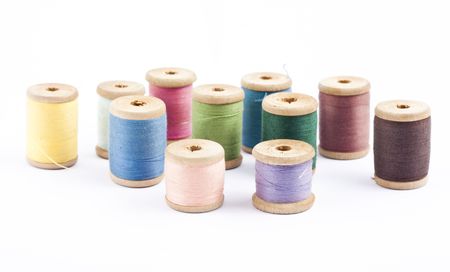 Wooden multicolored thread coils on white background