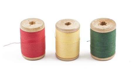 Three wooden multicolored thread coils on white background (red, yellow and green)の写真素材