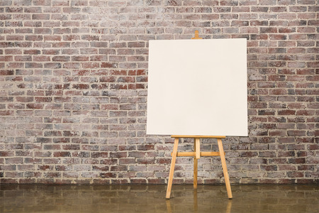 Easel with blank canvas on a brick wall backgroundの写真素材
