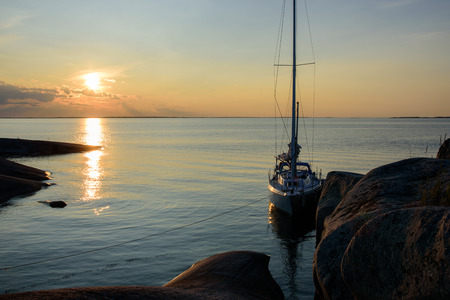 Sunset over a sailboat moored at small rocky islands in the outer part of the archipelago of Stockholm, Swedenの写真素材
