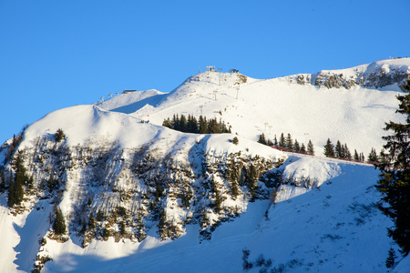 Low evening light over a skislope area where a mountain ridge is crossing the picture in front.の写真素材