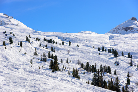 Wide area of unprepared ski slopes in the french alps. Scattered trees. A lift with cabins is going across the picture.の写真素材