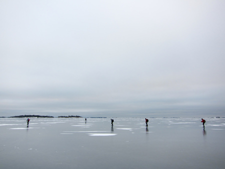 A group of people skating on newly frozen thin ice in the archipelago. Stockholm, Sweden.の写真素材