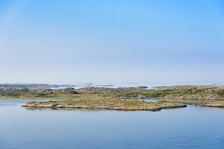 Rocky granite islands in a calm sea. Horizon over water and small skerries. Small tents on the closest island.の写真素材